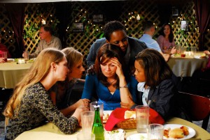 A gaggle of women cloistered around a table and hugging. No good can come from this.